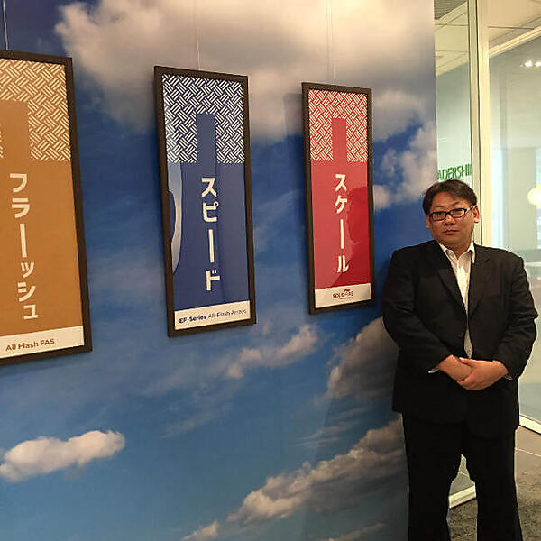 ネットアップ株式会社の神原氏。飾られているのは日本で作成したというフラッシュストレージ販促のための手拭いだ