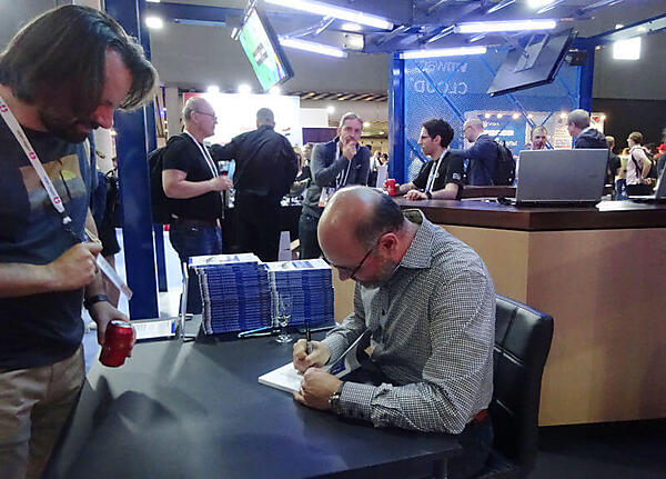 VMwareのブースで著作本にサインを入れるJoe Beda氏