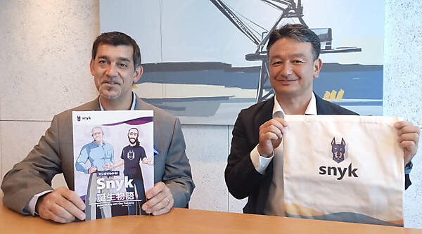 トートバッグとSnyk誕生のエピソードをマンガ化した冊子を持つMaira氏と秋山氏