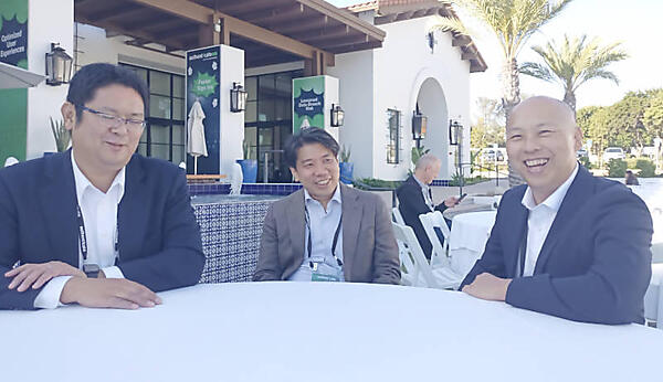 屋外のテーブルでインタビューに応じたISRのプレゼンター3名