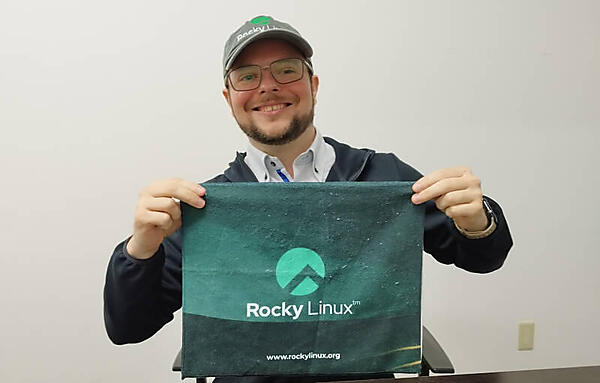 Brian Clemens氏が手に持っているのはRocky Linuxのタオル